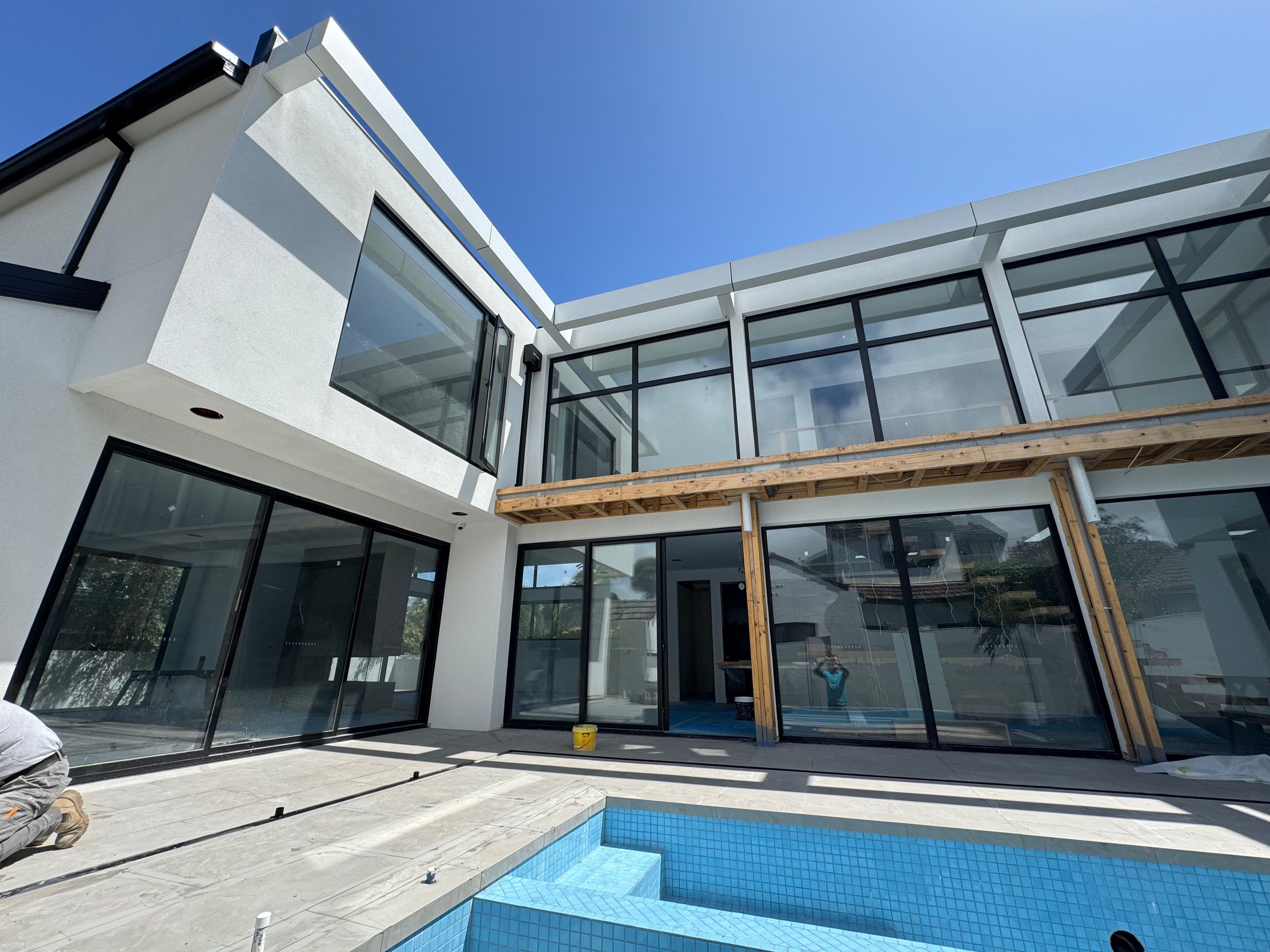 Newly finished house with black-framed glazing and a new pool, paving still part-laid