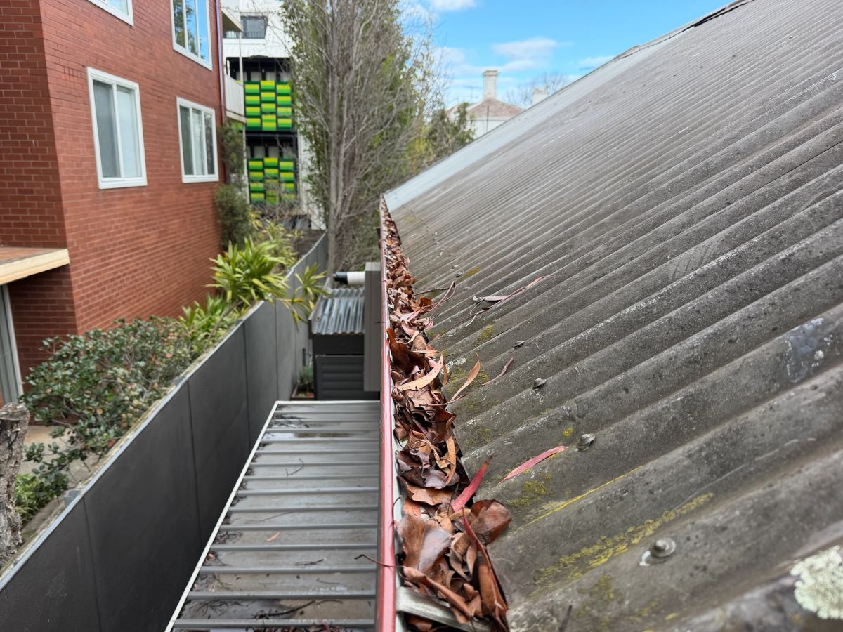 Gutter on Wrexham Road, Windsor hidden under a metal roof sheet that overhangs and covers the channel