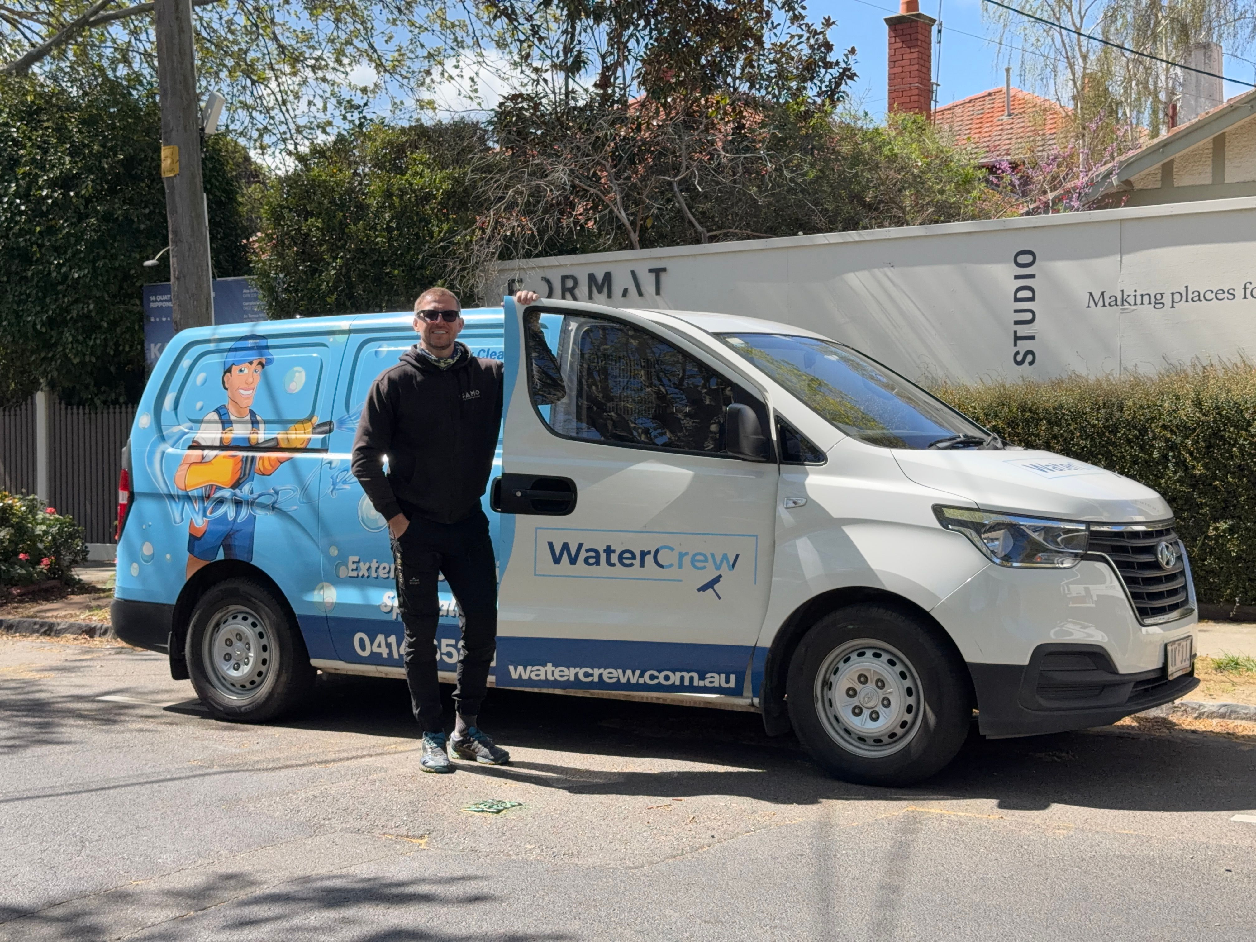 WaterCrew technician with cleaning equipment on a tree-lined Ripponlea street