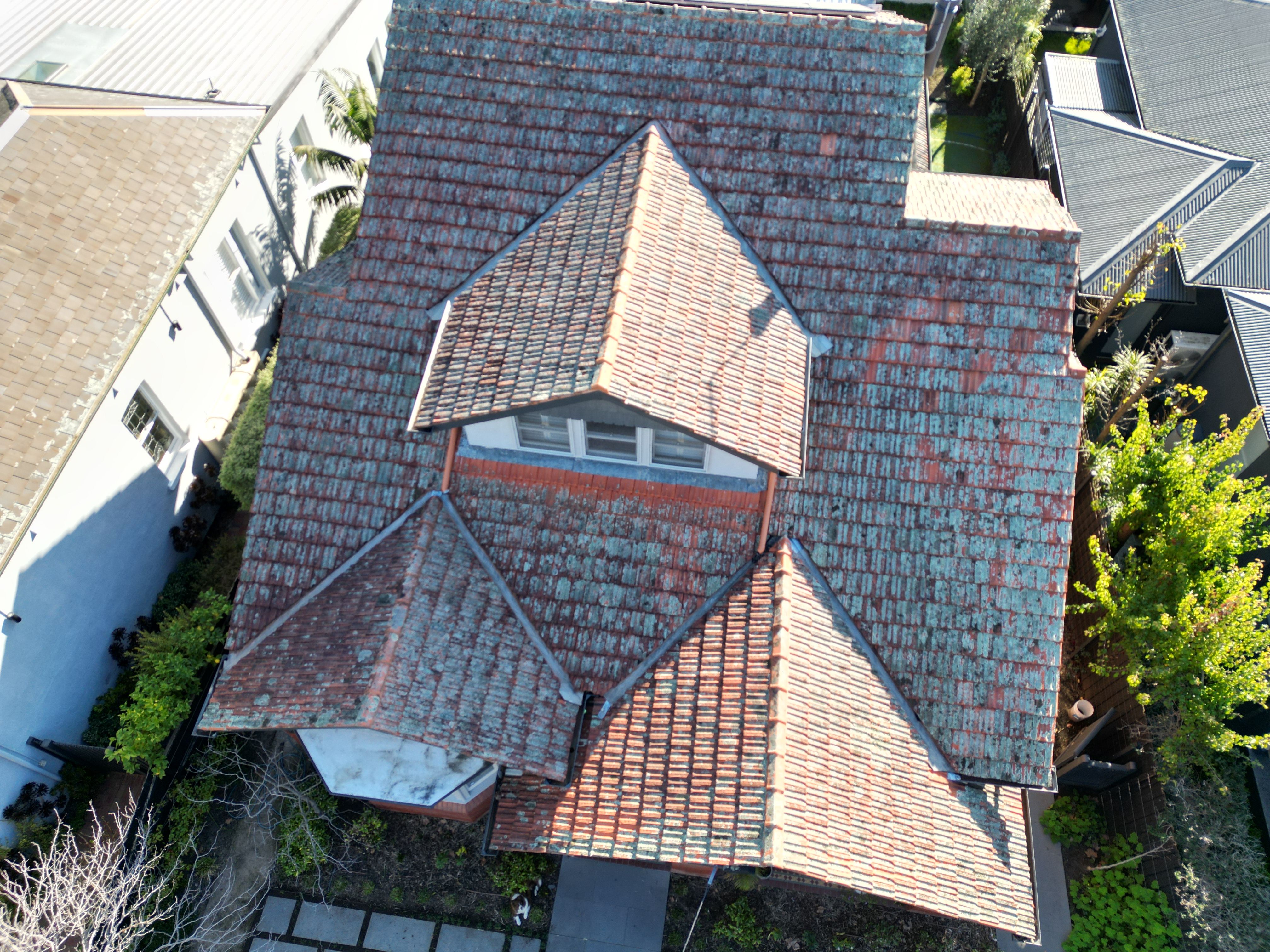 Terracotta roof from above, mottled blue-green with lichen across every face