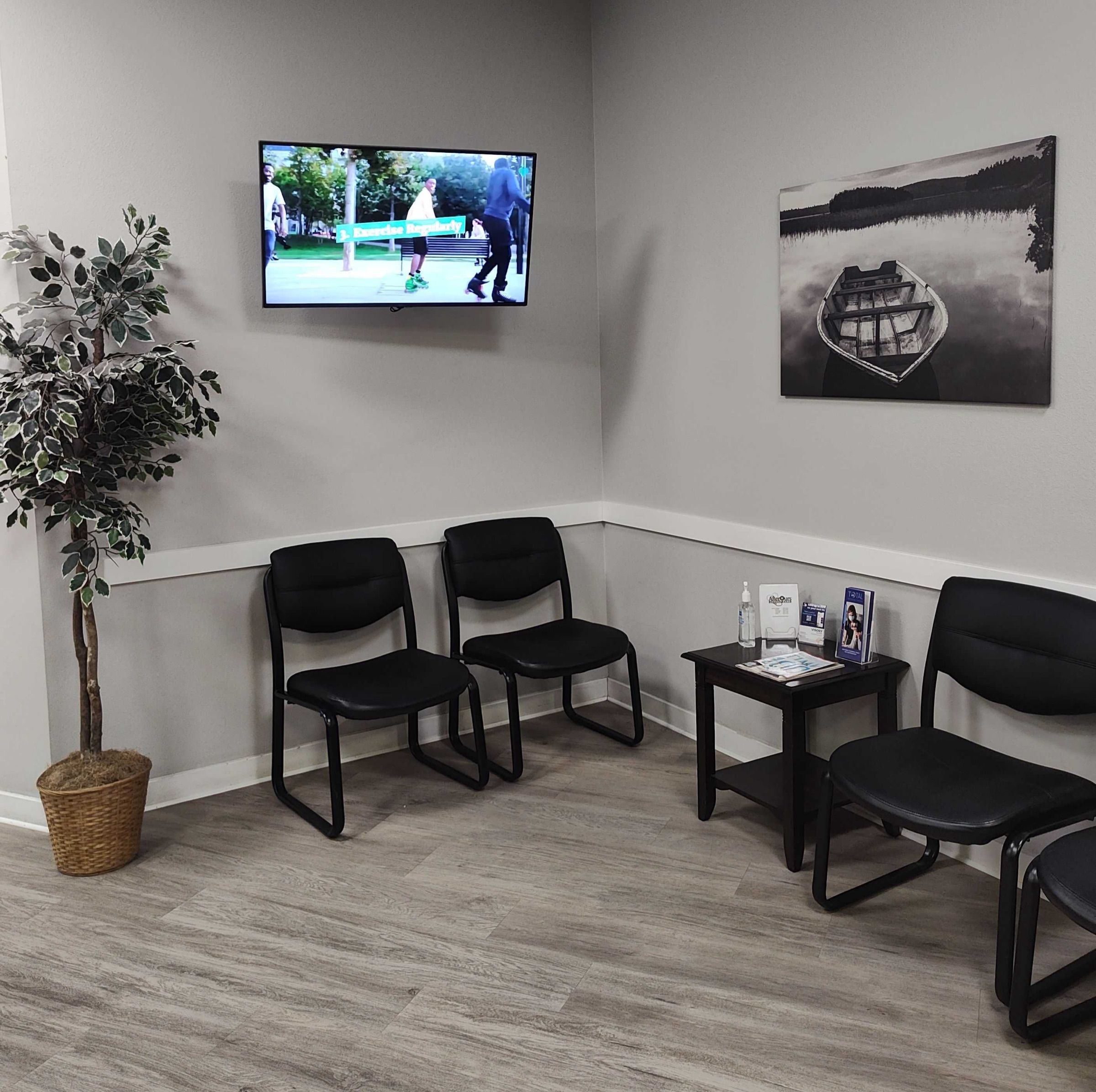 Waiting area with chairs, a plant and a wall-mounted TV