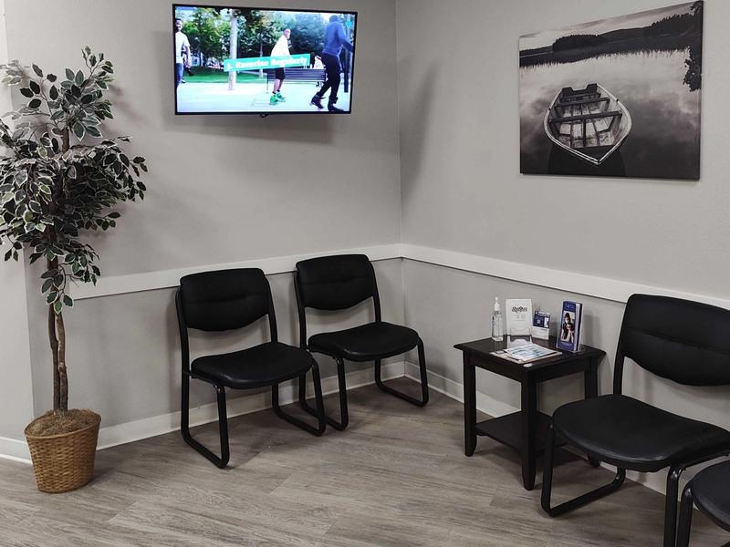Waiting area with chairs, a plant and a wall-mounted TV
