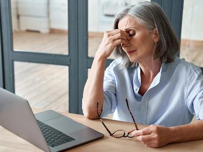 Middle-aged woman rubbing her eyes while sitting at a desk - representing exhaustion, low energy, and adrenal imbalance improved through functional medicine treatment for fatigue in Denver, Colorado Springs, and Fort Collins