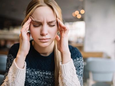 Woman sitting with eyes closed and hands on temples - representing chronic headaches, light sensitivity, and pain relief through functional medicine treatment for migraines in Denver, Colorado Springs, and Fort Collins