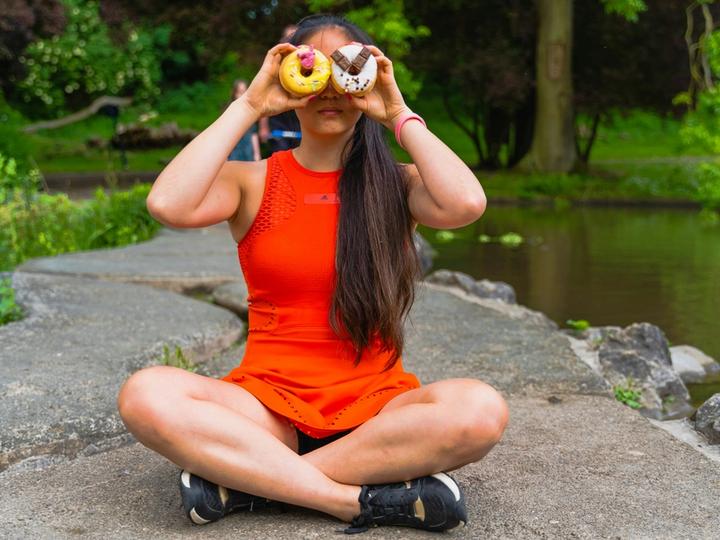 Women outside holding donuts over her eyes thinking about getting healthy