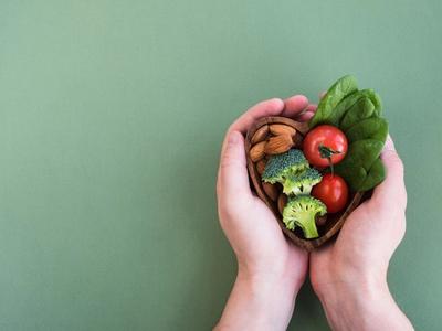 Hands holding heart-shaped bowl of vegetables, nuts, and greens - symbolizing heart health, balanced nutrition, and improved circulation through functional medicine cardiovascular care in Denver, Colorado Springs, and Fort Collins