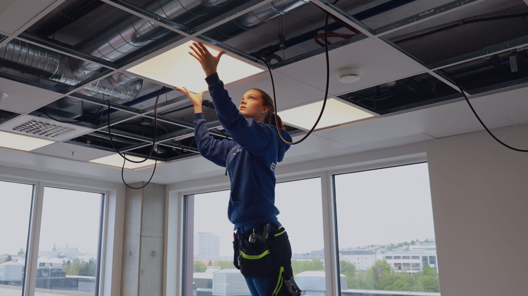 Elektriker fra Elteam i Trøndelag, en del av Nimlas, installerer et lysarmatur i et kontorlokale