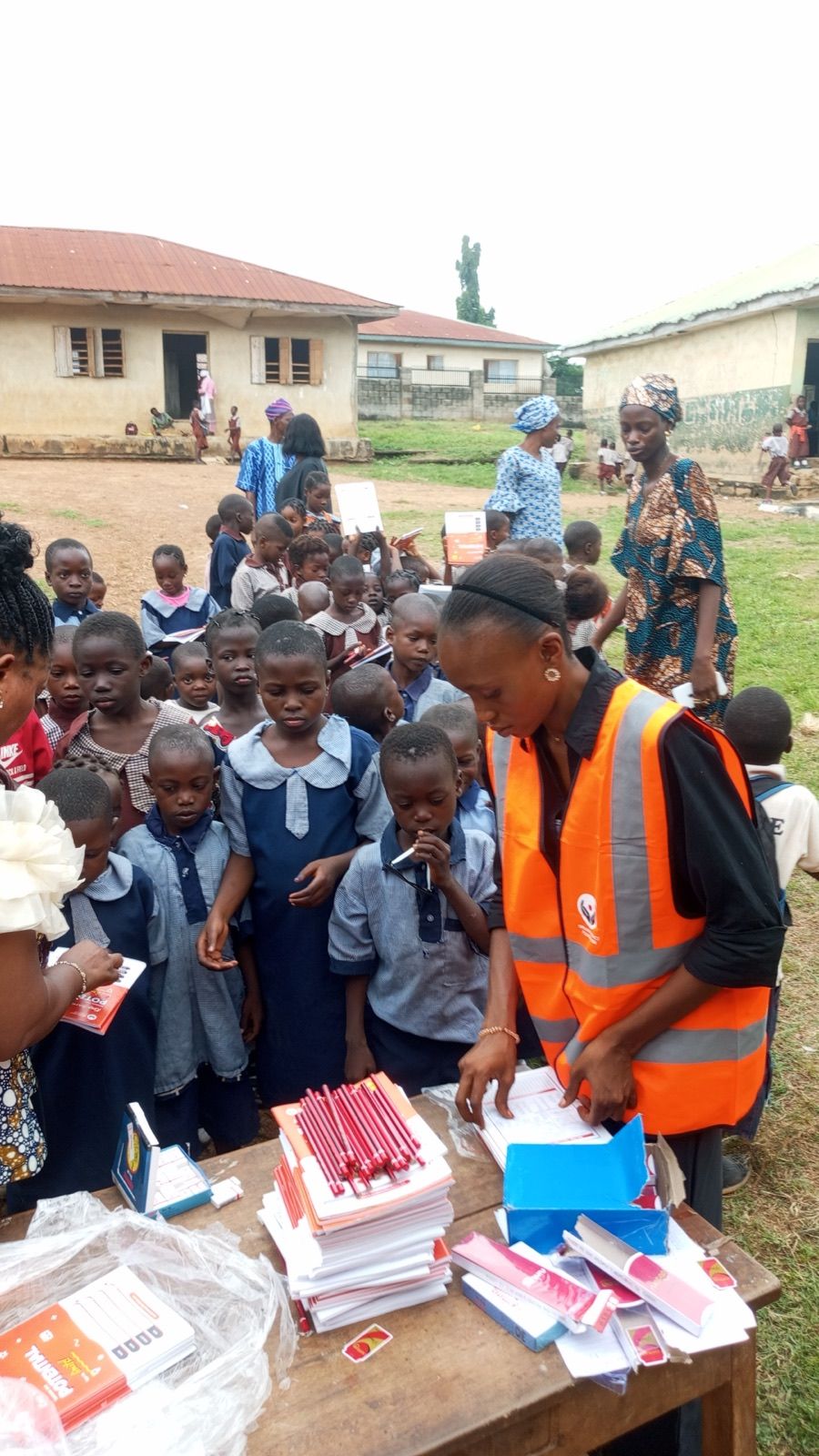 A volunteer at a table with stacks of notebooks and pencils
