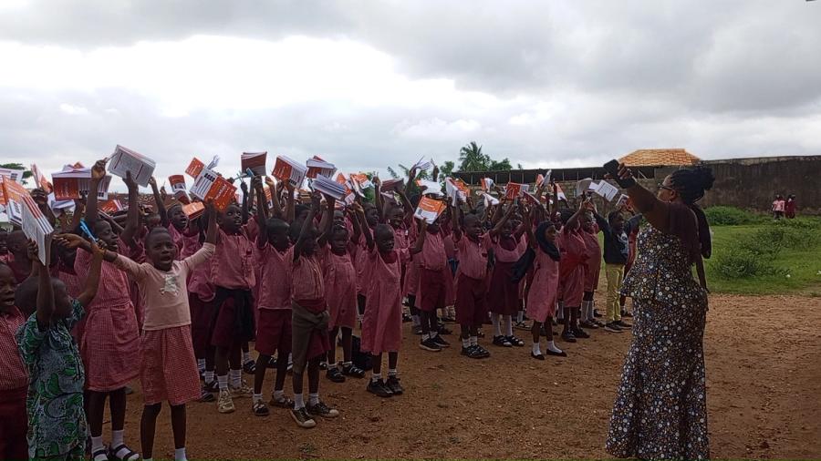 Pupils in pink school uniforms raising their new notebooks