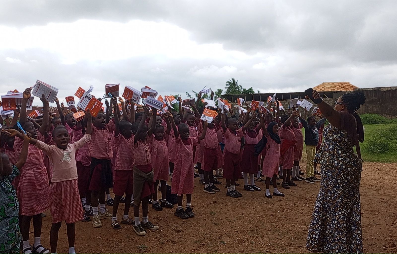 Pupils in pink school uniforms raising their new notebooks
