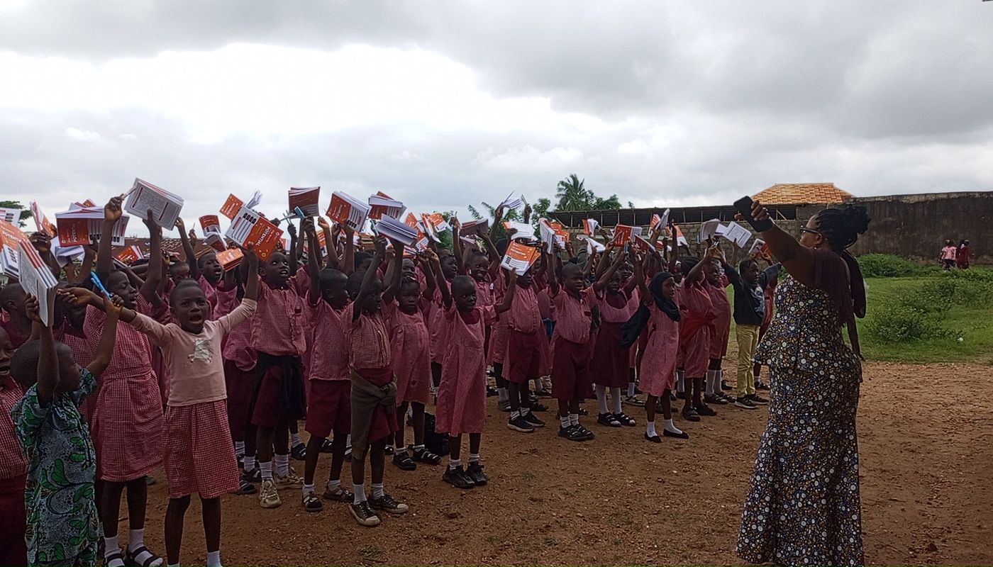 Pupils in pink school uniforms raising their new notebooks