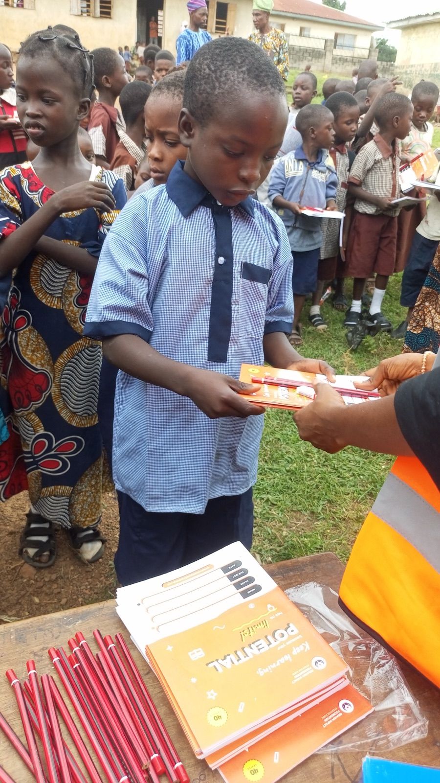 A pupil receiving a notebook from a volunteer