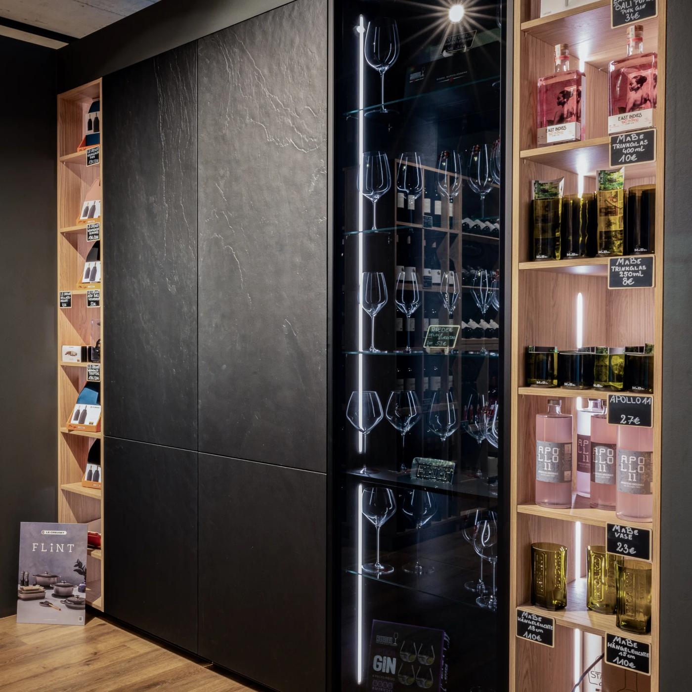 Vinothek im Thoki Studio mit beleuchteter Wein-Glas-Vitrine zwischen Holz-Wein-Regalen, Küche & Weinkonzept