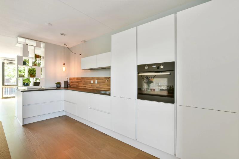Grifflose weiße Küche von Thoki mit Holz-Arbeitsplatte, integriertem Backofen und modernem L-förmigem Design