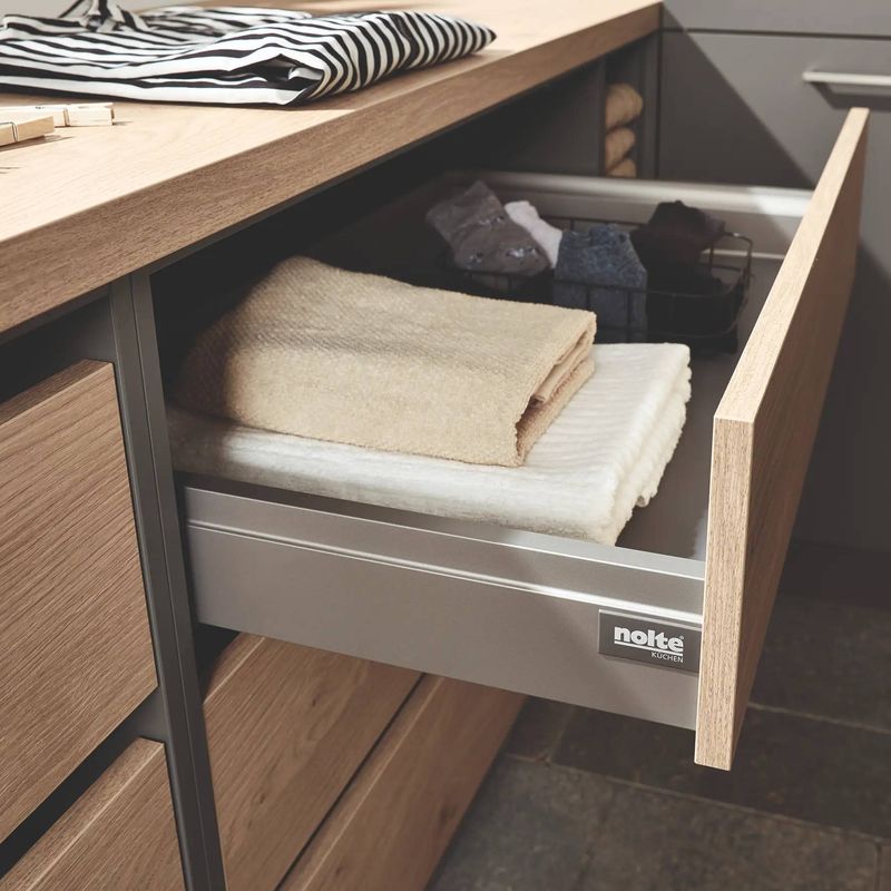 Nolte Küchen Schublade mit Handtuchfächern und gefalteten Handtüchern in Beige und Grau