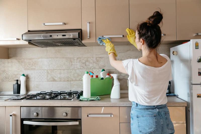 Frau reinigt matte Küchenfront mit Mikrofasertuch und Hausmitteln, streifenfreie Pflege-Tipps von Thoki