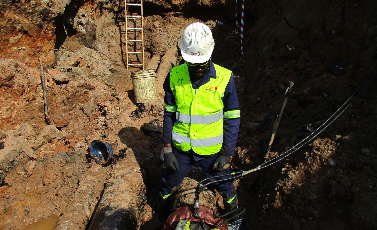 Gecric Integrity technician inspecting exposed pipelines in an excavation