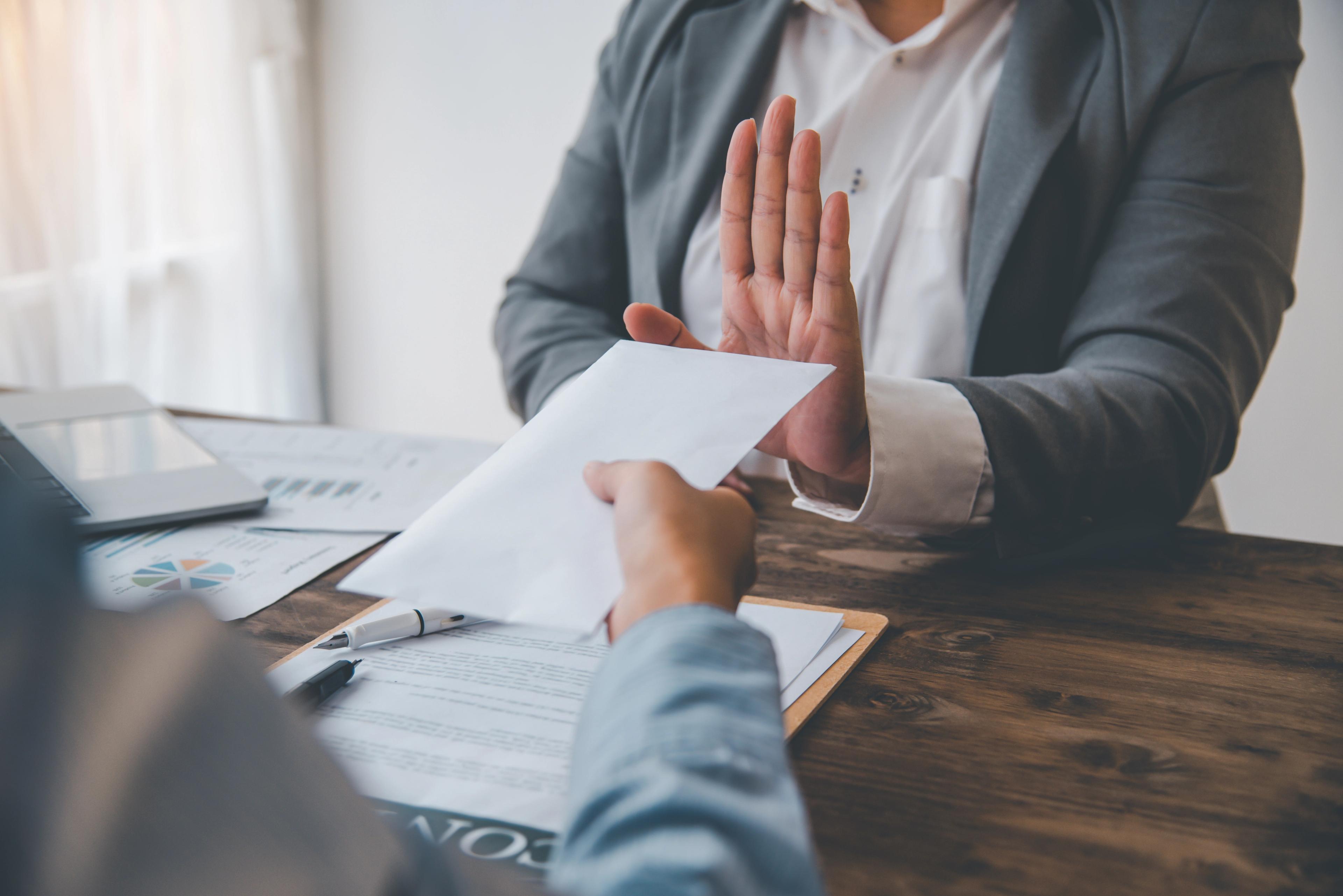 A professional refusing a cash envelope during a contract discussion