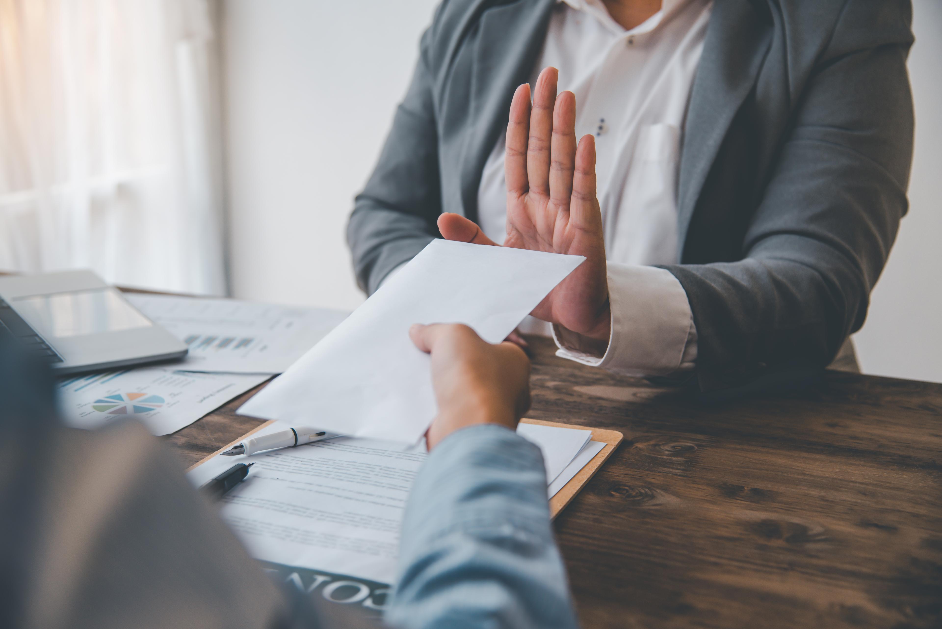A professional refusing a cash envelope during a contract discussion
