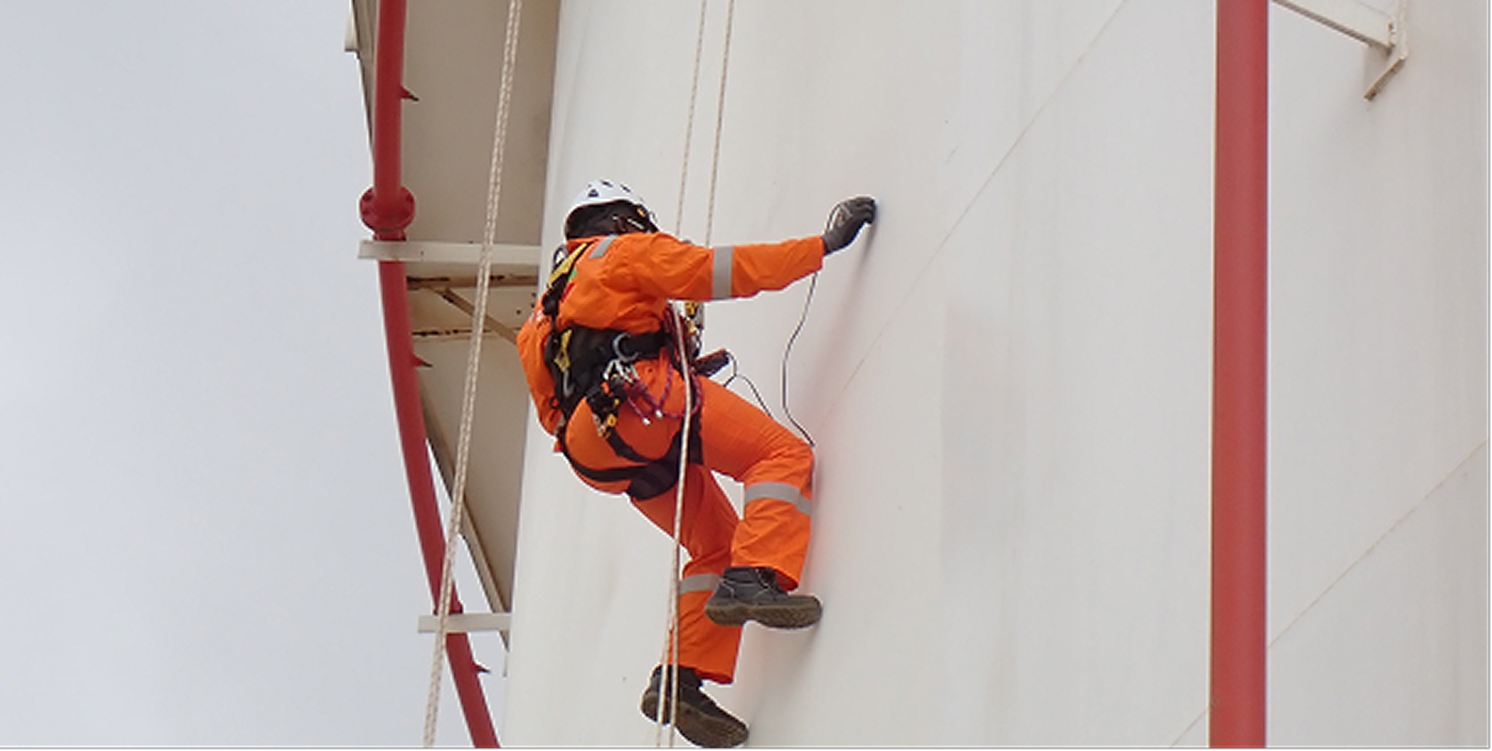 Rope access technician working at height on an industrial structure