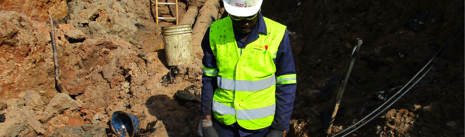 Gecric Integrity technician inspecting exposed pipelines in an excavation
