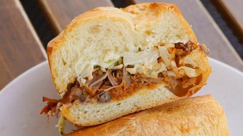 Pulled pork torta on a torpedo bun with chipotle BBQ sauce, beans, and slaw.