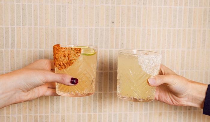 Two people cheers with their margaritas in hand against a wall in Marlos Tacos Edmonton