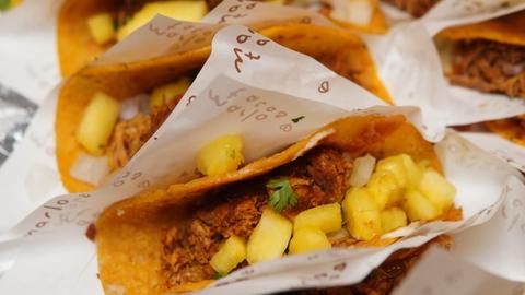 many tacos lined up in a box, each in an individual liner, closely together 