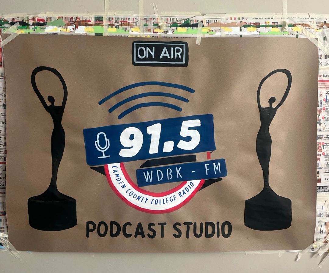 Banner for 91.5 WDBK-FM Camden County College Radio Podcast Studio, with a painted On Air sign and two award statuettes.