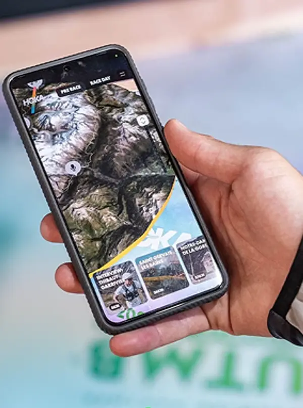 Close-up of a person holding a phone showing the HOKA UTMB WebAR experience