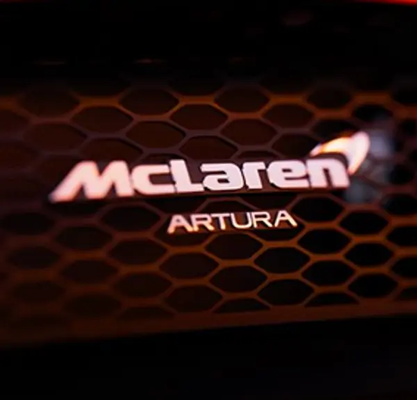 Close-up 3D render of the McLaren badge on the front grille of the Artura Spider