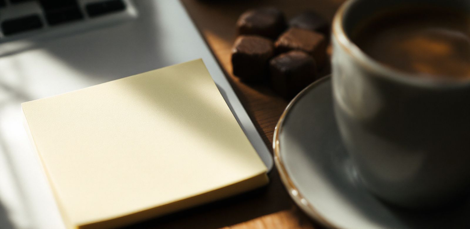 Blank sticky notes, a closed laptop, and espresso on a desk during GTM planning.