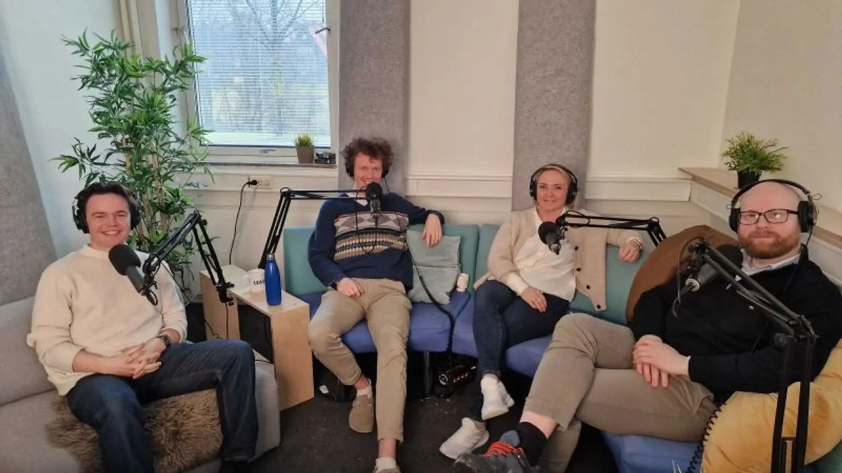 Four people sitting on a couch recording a podcast