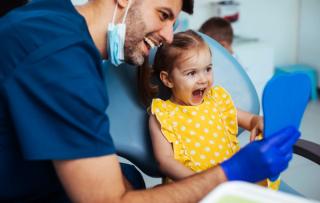 Dentist showing young patient their teeth in a mirror
