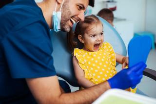 Dentist showing young patient their teeth in a mirror