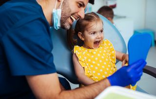 Dentist showing young patient their teeth in a mirror