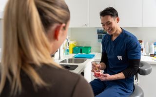 Image of Dr Chris Karikios showing a dental patient their smile preview in our clinic in CBD Sydney.