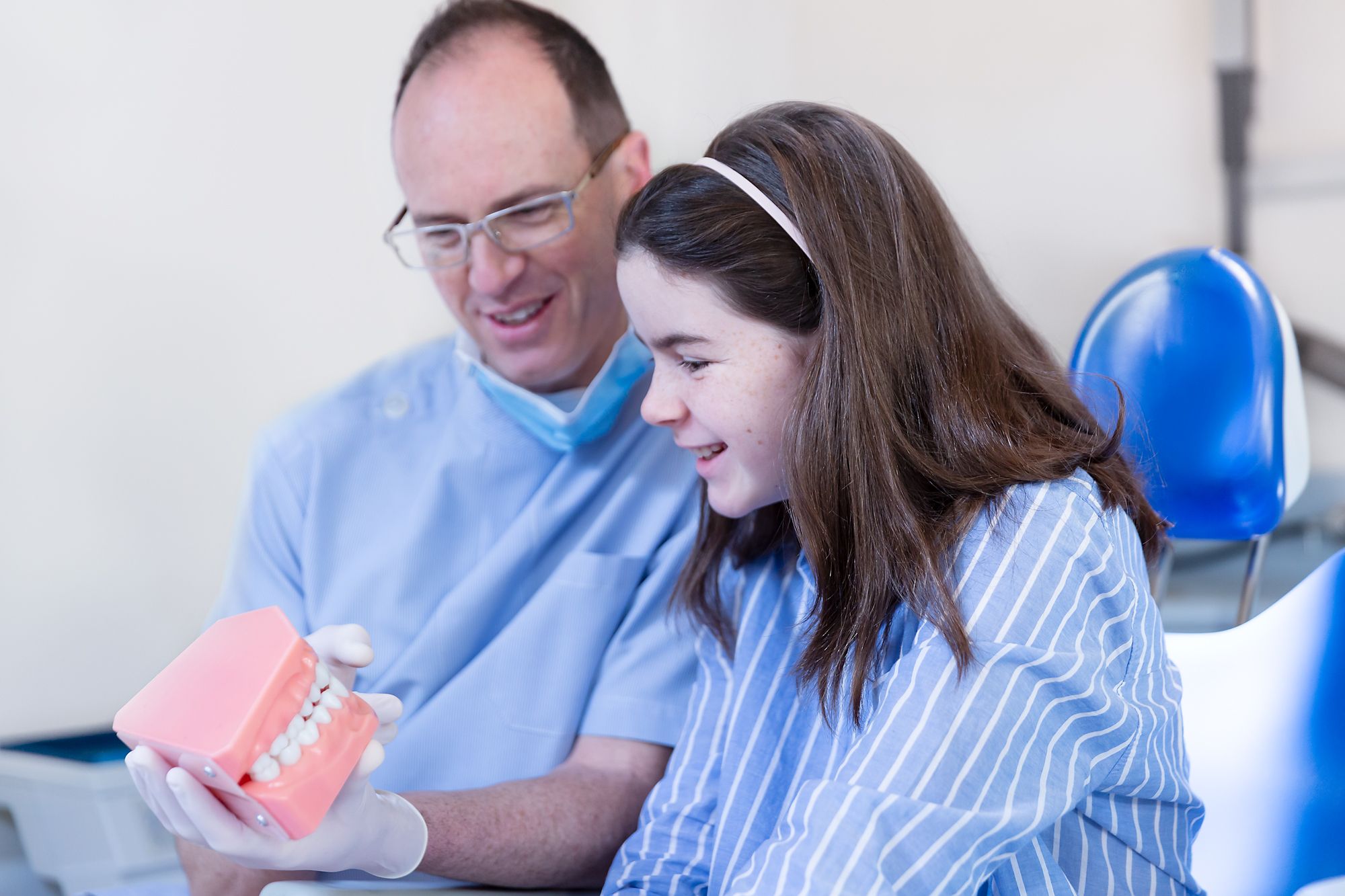 Image of a dentist holding a 3D model of a set of teeth.