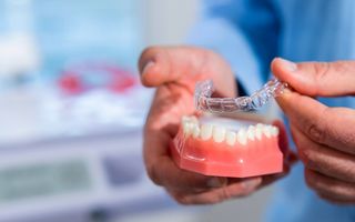 Image of Dr. Adam Sibio showing a model of teeth with an Invisalign® aligner.