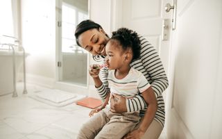 Parent teaching a child how to brush their teeth