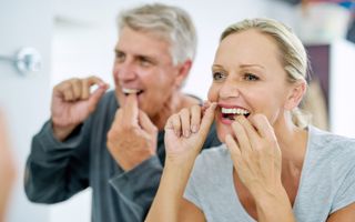 Couple flossing together to maintain their oral health.