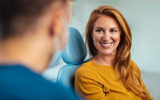Happy patient talking with dentist post dental crown treatment