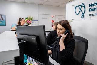 Image of our receptionist team at the front counter of National Dental Care Box Hill picking up a call.