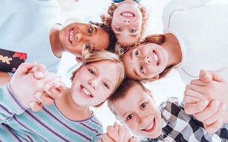 Group of kids looking down at the camera holding hands