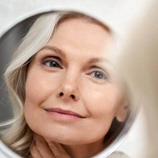 Image of a elderly woman admiring herself in a mirror.