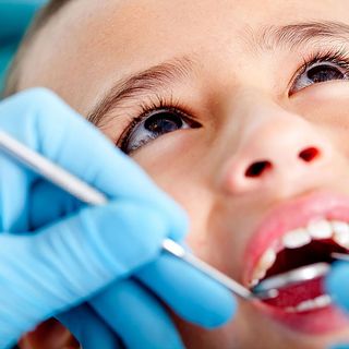 Image of child being inspected by a dentist.