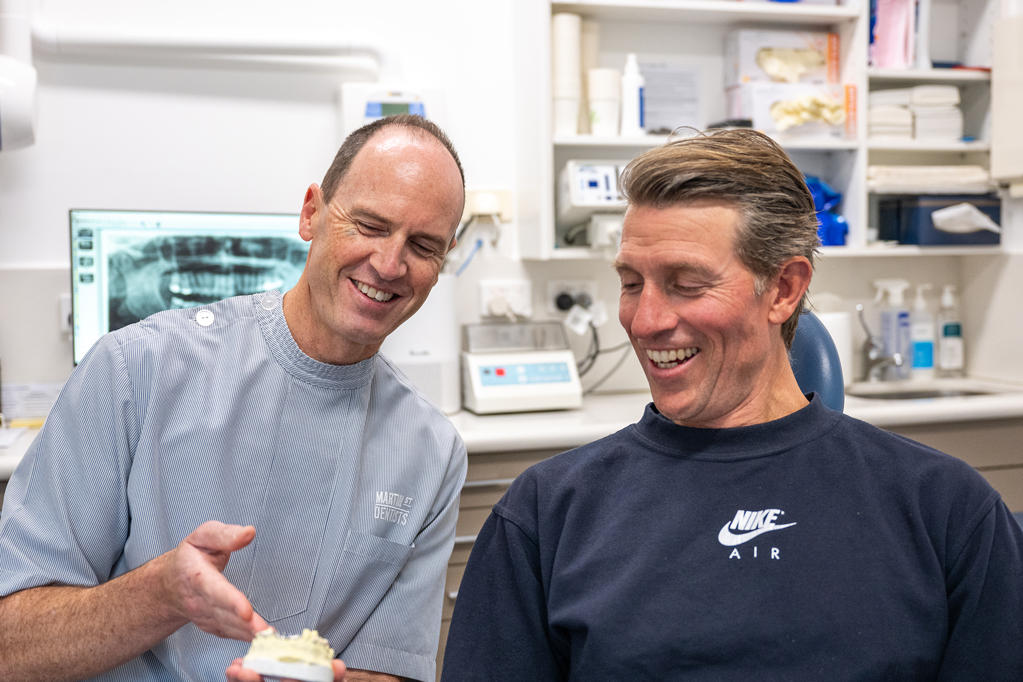 Image of Dr. Tim Nicolls with his patient showing a model of teeth.