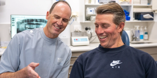 Image of Dr. Tim Nicolls with his patient showing a model of teeth.