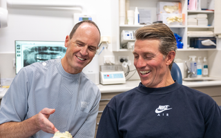 Image of Dr. Tim Nicolls with his patient showing a model of teeth.