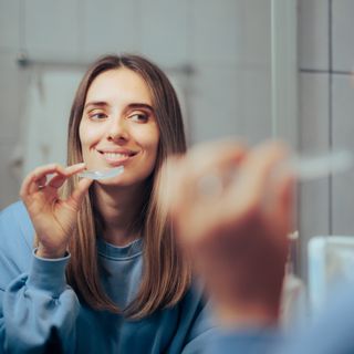 A user of orthodontics in their bathroom putting on their aligners.